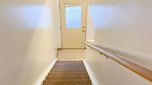Eine Treppe mit Geländer, die zu einer Tür mit Fenster führt.