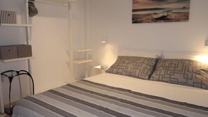 Une chambre à coucher avec un lit, une table de chevet, une étagère et un tableau accroché au mur.