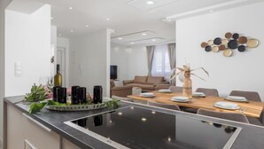 A modern kitchen with a central island, a dining area with a wooden table, and a living space with a sofa and TV. - Villa Lea by Interhome (Crikvenica/Jadranovo)