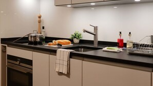 Une cuisine moderne avec un évier en acier inoxydable, un moulin à poivre en bois, une miche de pain et une plante en pot.