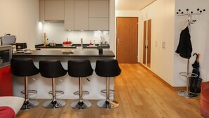 Une cuisine moderne dotée d’un îlot central, de tabourets de bar et d’un porte-manteau.