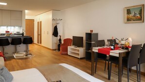 Une chambre d’hôtel moderne équipée d’un lit, d’un coin repas, d’une télévision et d’un porte-manteau.