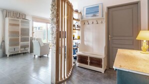 Una habitación amplia con un separador de madera, un armario blanco, una silla y un escritorio con una lámpara.