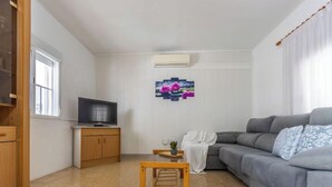 Ett vardagsrum med en grå soffa, ett träbord och en tv som står på ett träskåp.