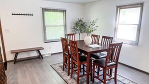 A dining area with a wooden table and chairs, a bench, and a potted plant.
