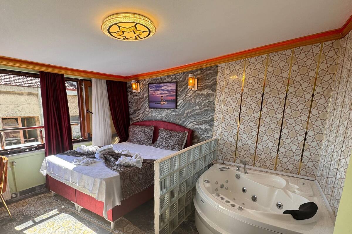 A bedroom with a bed, a bathtub, and a window.