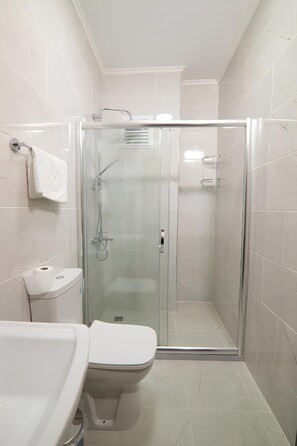 A modern bathroom with a glass-enclosed shower, a toilet, and a sink. - Gur Royal Suit Aparts (Istanbul)
