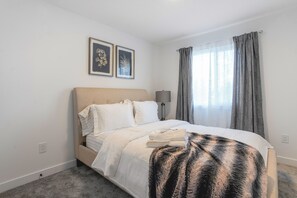Une chambre à coucher avec un lit, une lampe de chevet et deux tableaux encadrés accrochés au mur.