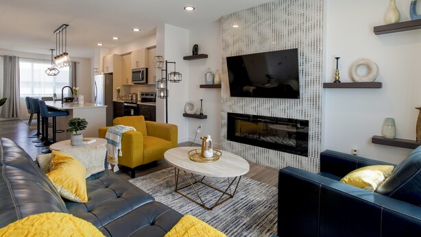 Een moderne woonkamer met een bank, een gele fauteuil en een aan de muur bevestigde televisie.