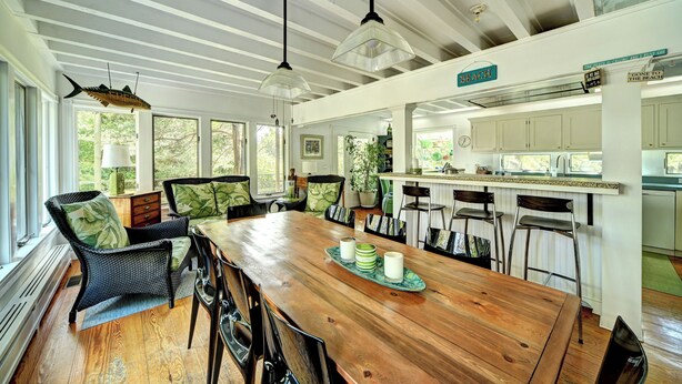 A spacious dining area with a wooden table, chairs, and hanging pendant lights. - Steps to the beach!  Relax and Enjoy! (Amagansett)