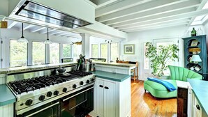 A kitchen with a stove, oven, and a green chair. - Steps to the beach!  Relax and Enjoy! (Amagansett)