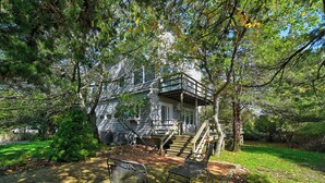 A house with a covered porch, a staircase leading to the entrance, and a small garden area with a bench. - Steps to the beach!  Relax and Enjoy! (Amagansett)