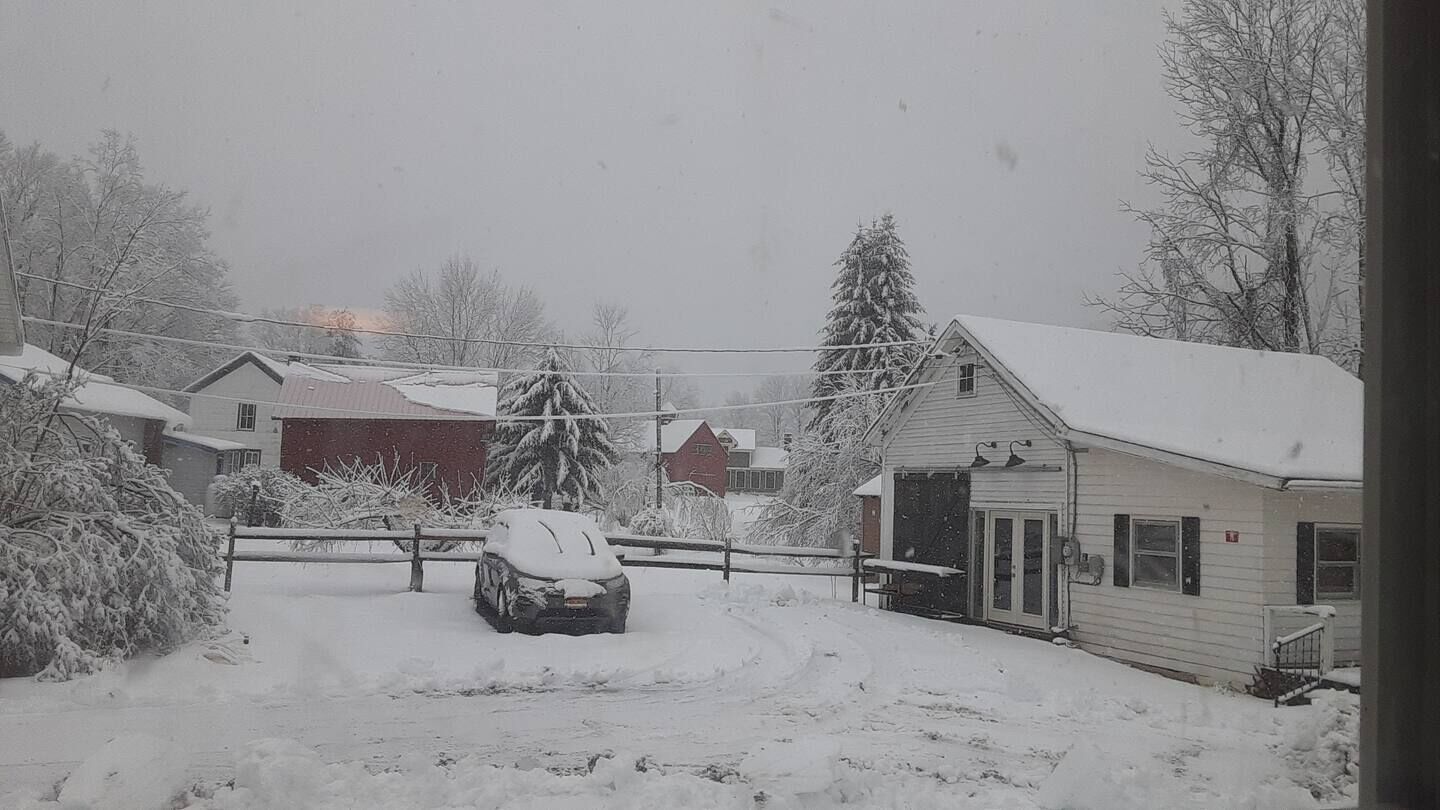Un quartier résidentiel avec des maisons et une voiture recouverte de neige.