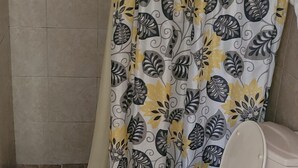 Ein Badezimmer mit Toilette, einer Duschkabine mit Blumenmuster und gefliesten Wänden und Boden.