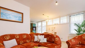 Una sala de estar con un sofá modular, una mesa de centro redonda de madera y un cuadro en la pared.