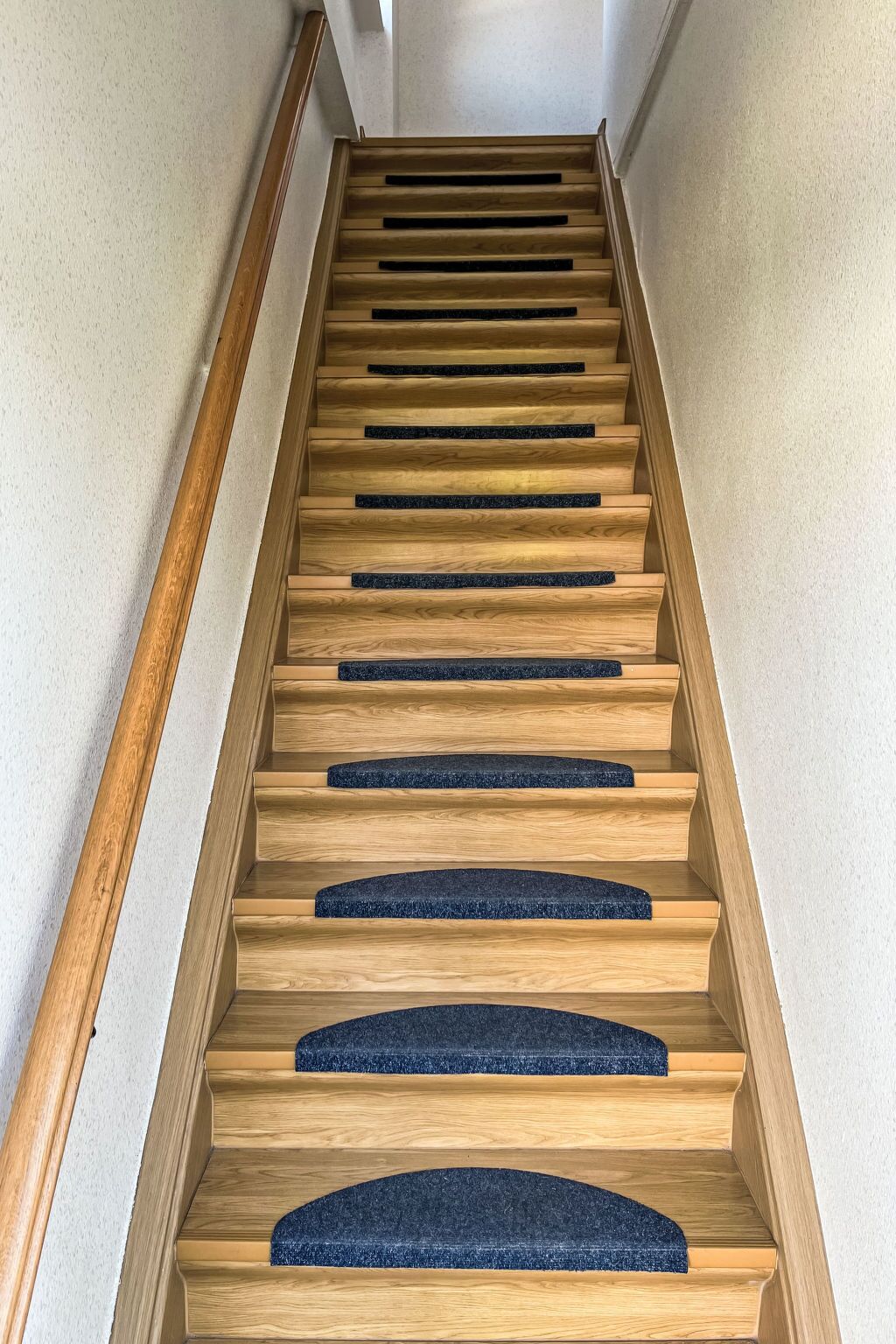 Una escalera de madera con elegantes pasillos de moqueta azul oscuro.