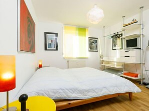 Un dormitorio moderno con cama, mesita de noche, lámpara y una obra de arte.