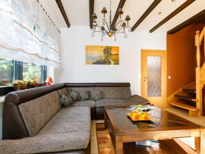 A modern living room with a sectional sofa, a glass coffee table, a chandelier, and a painting on the wall. - Vacation home Petra by Interhome (Neeberg)
