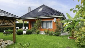 A house with a sloped roof, a satellite dish, and a well-maintained garden with various plants and a lawn. - Vacation home Petra by Interhome (Neeberg)