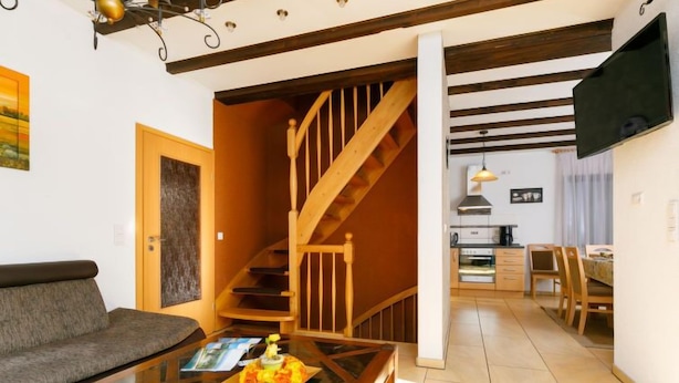 A living room with a sofa, coffee table, and a staircase leading to a kitchen area. - Vacation home Petra by Interhome (Neeberg)