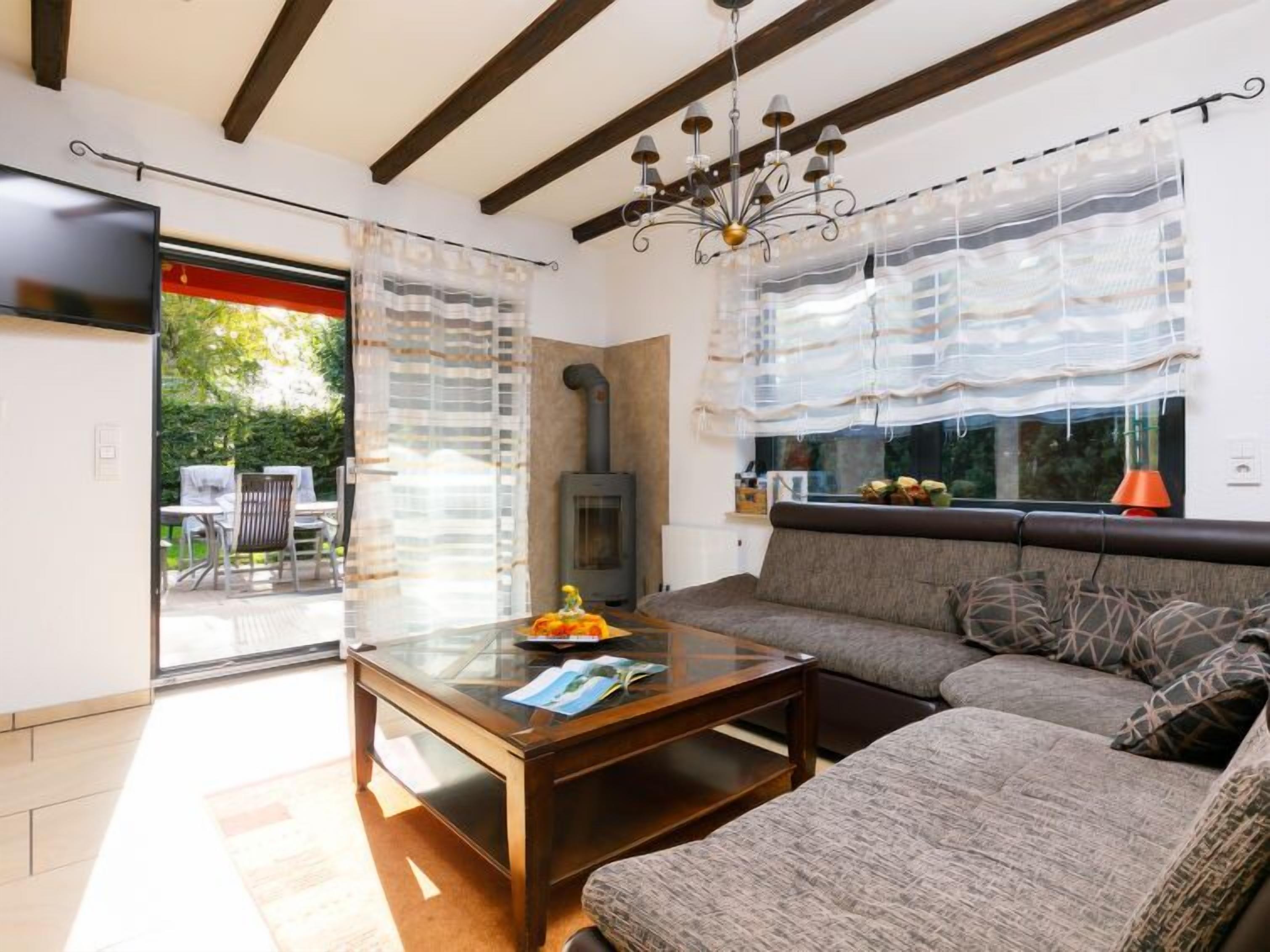 Una sala de estar con un sofá, una mesa de centro de vidrio, una chimenea y un televisor montado en la pared.