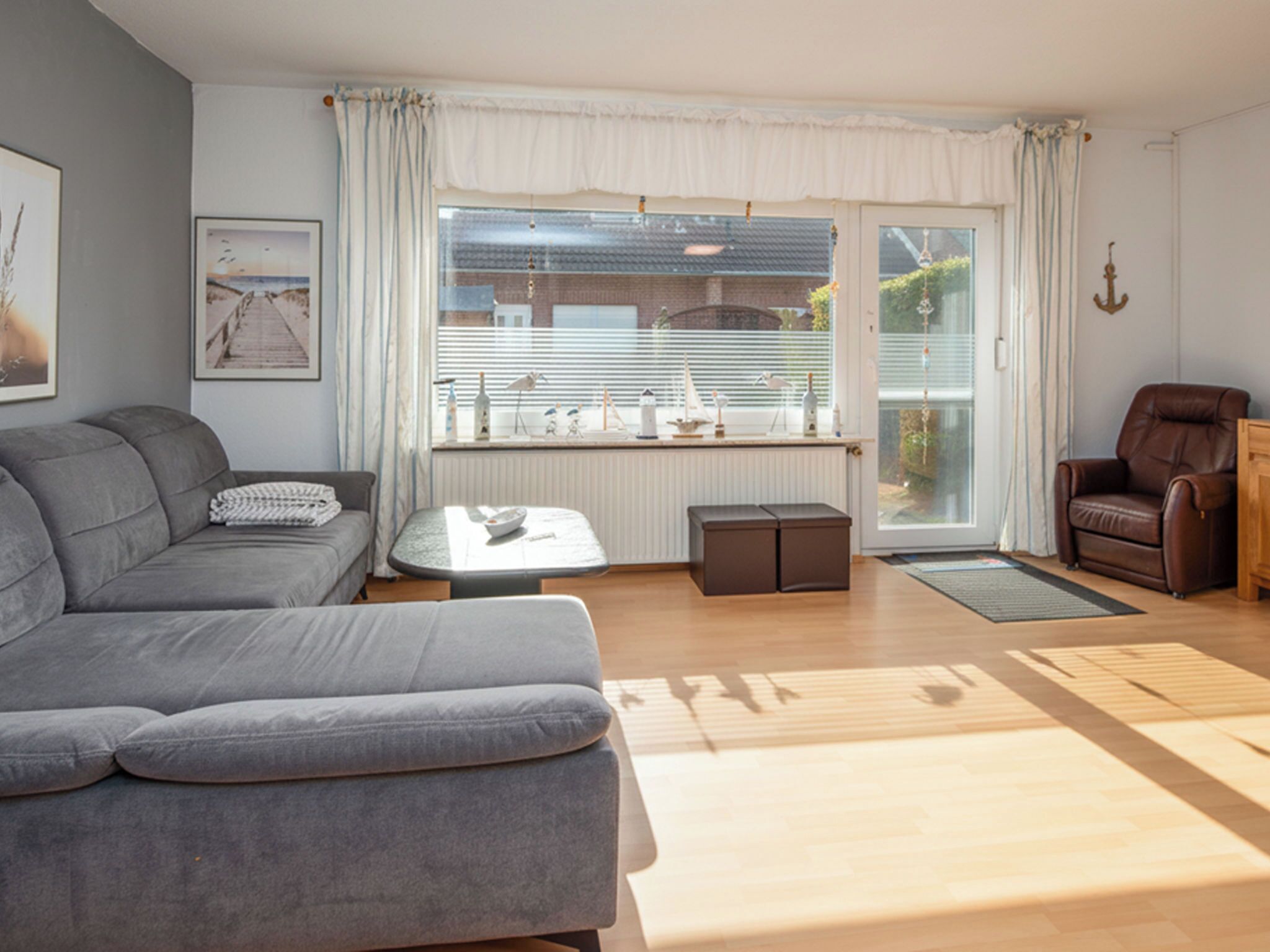 A modern living room with a grey sofa, a small coffee table, a brown leather chair, and a window with blinds.