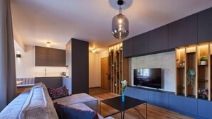 A modern living room with a sofa, a coffee table, and a TV mounted on the wall. - Summit View Lounge & Alcove by Interhome (Pec pod Snezkou)