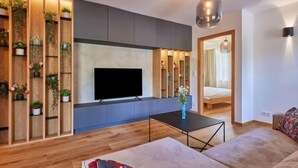 A modern living room with a flat-screen TV, wooden shelving with plants, a coffee table, and a sofa. - Summit View Lounge & Alcove by Interhome (Pec pod Snezkou)