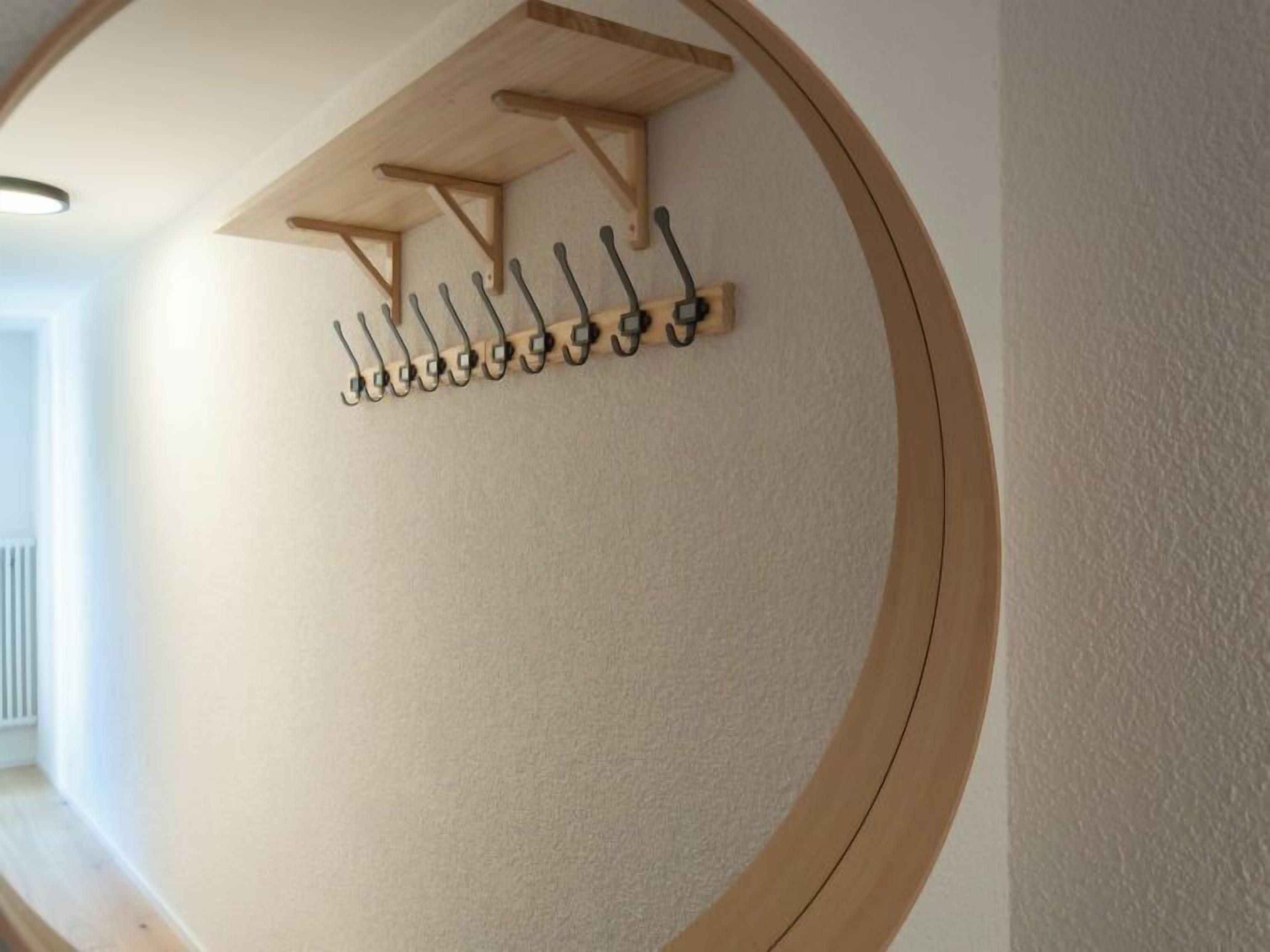 A circular wall with a wooden shelf holding multiple hooks.