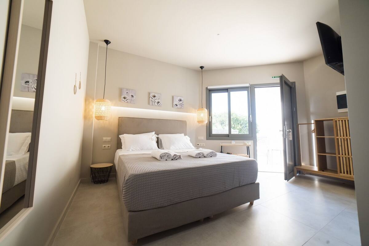 Un dormitorio moderno con una cama grande, lámparas de noche, una mesita redonda y un armario.