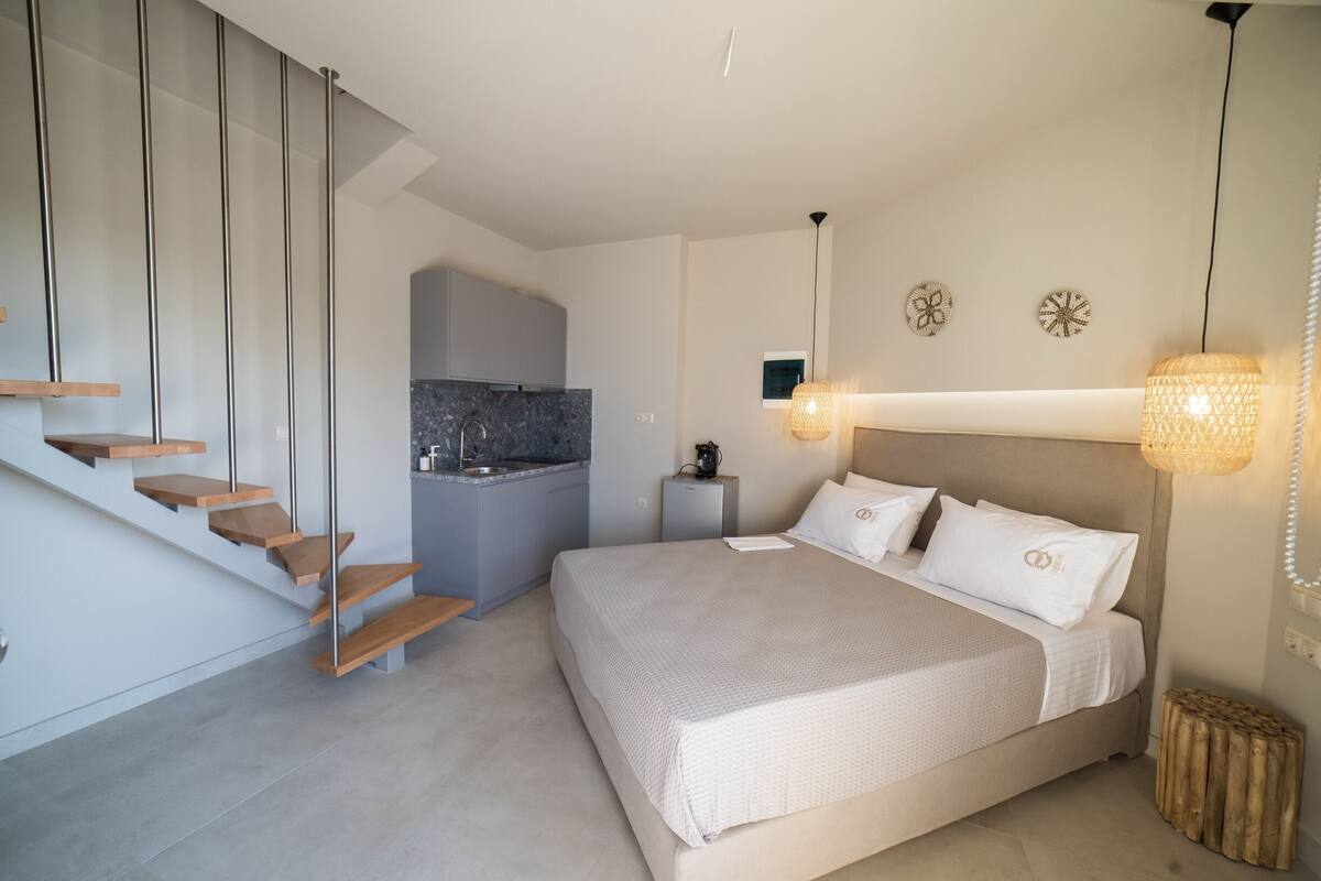 Un dormitorio moderno con una cama grande, un escritorio integrado y una zona de cocina.