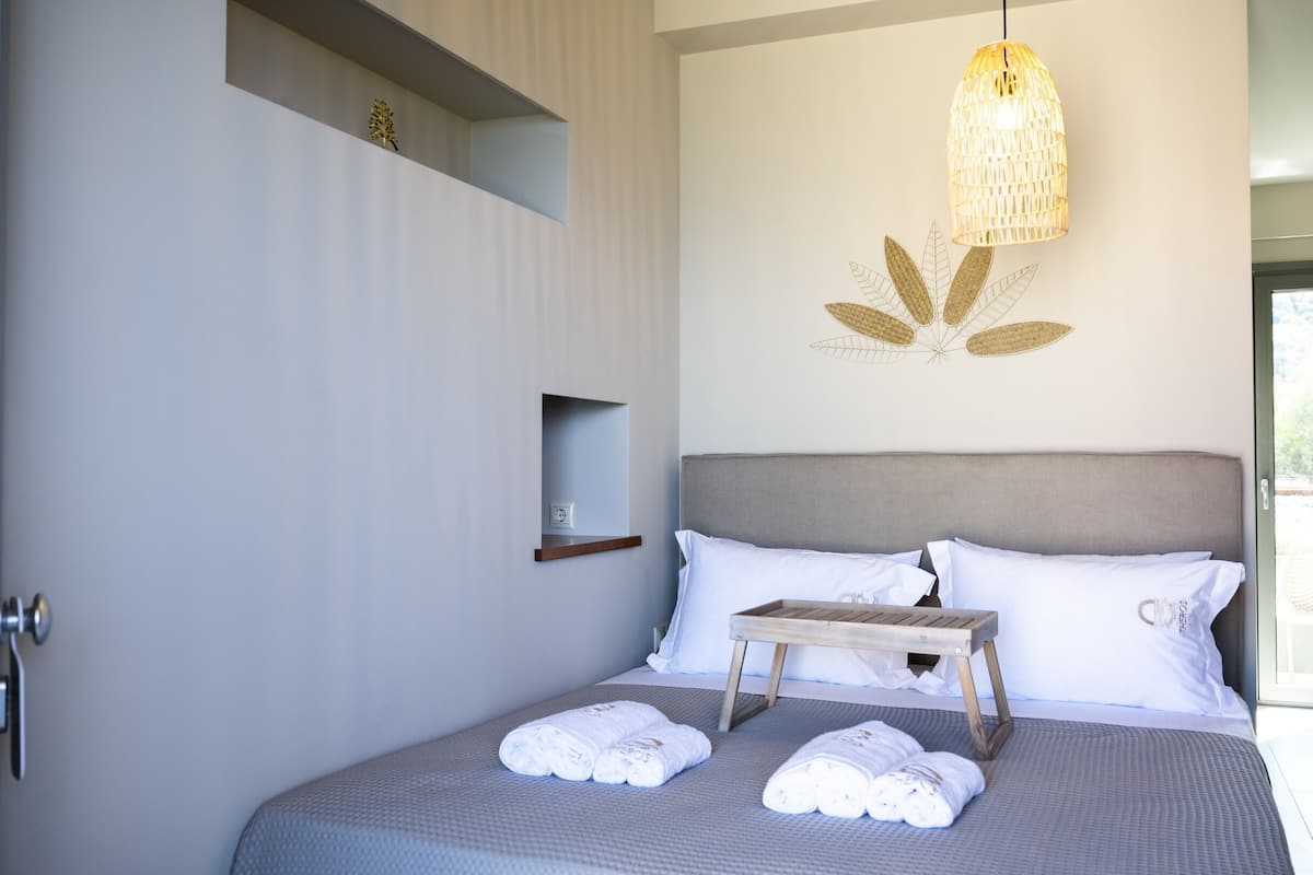 Un dormitorio moderno con cama, almohadas blancas, mesita de noche y lámpara de pared.