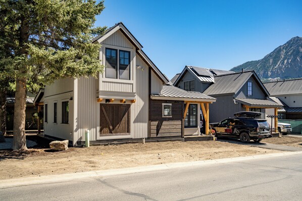 A two-story house with a large garage, a covered porch, and a mountain backdrop. - The Mariposa-Valerian Bundle at Academy Place (Crested Butte)