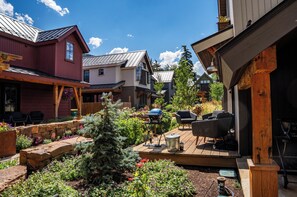 A residential area with a wooden deck, outdoor seating, and a barbecue grill.