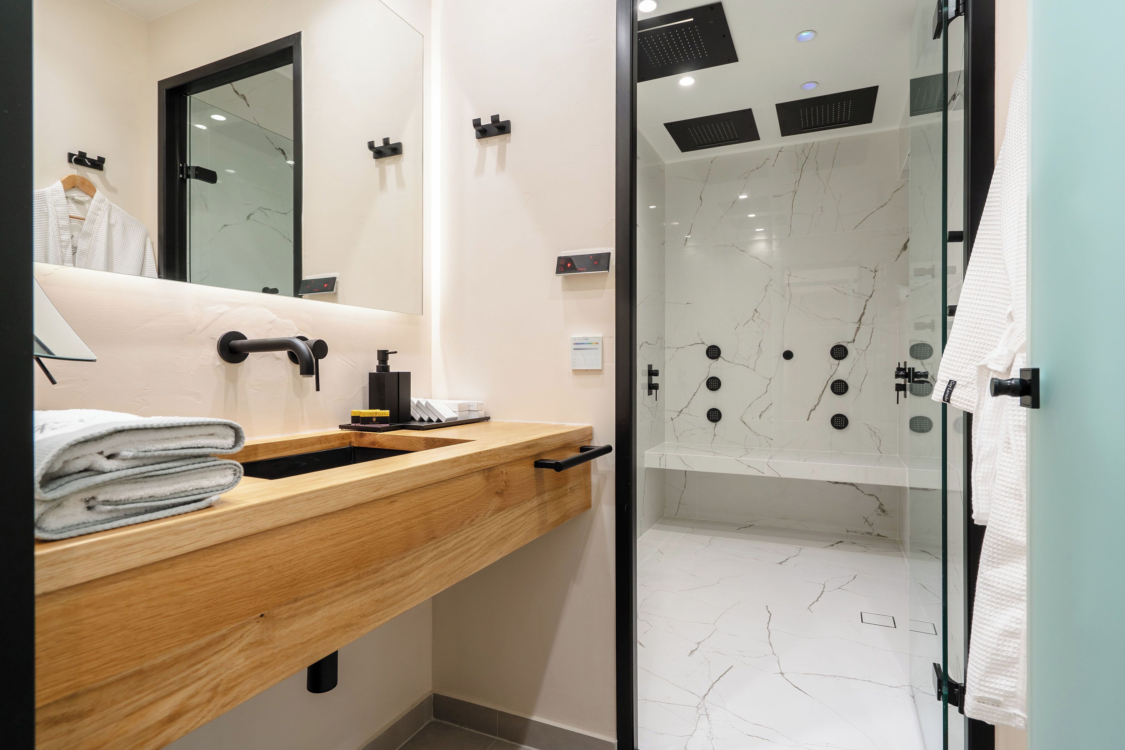 Ein modernes Badezimmer mit einem Holzkosmetikschrank, einem Spiegel, einem Waschbecken und einer Dusche mit Glastrennwand.