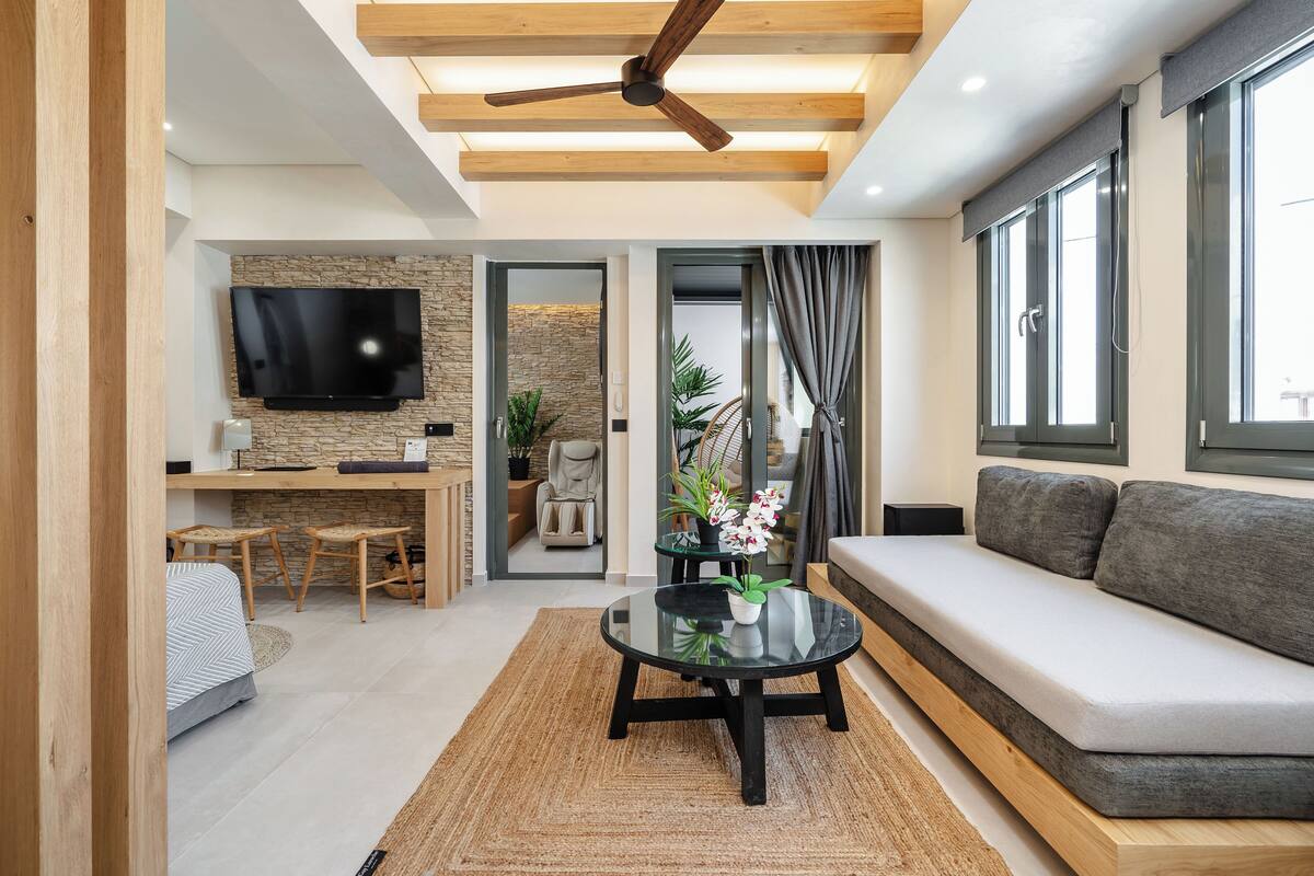 A modern living room with a sofa, a coffee table, a TV, and a dining area.