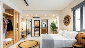 A modern bedroom with a large bed, a wardrobe, a bathroom, and a view of the kitchen. - Legato Spa Suites (Naxos)