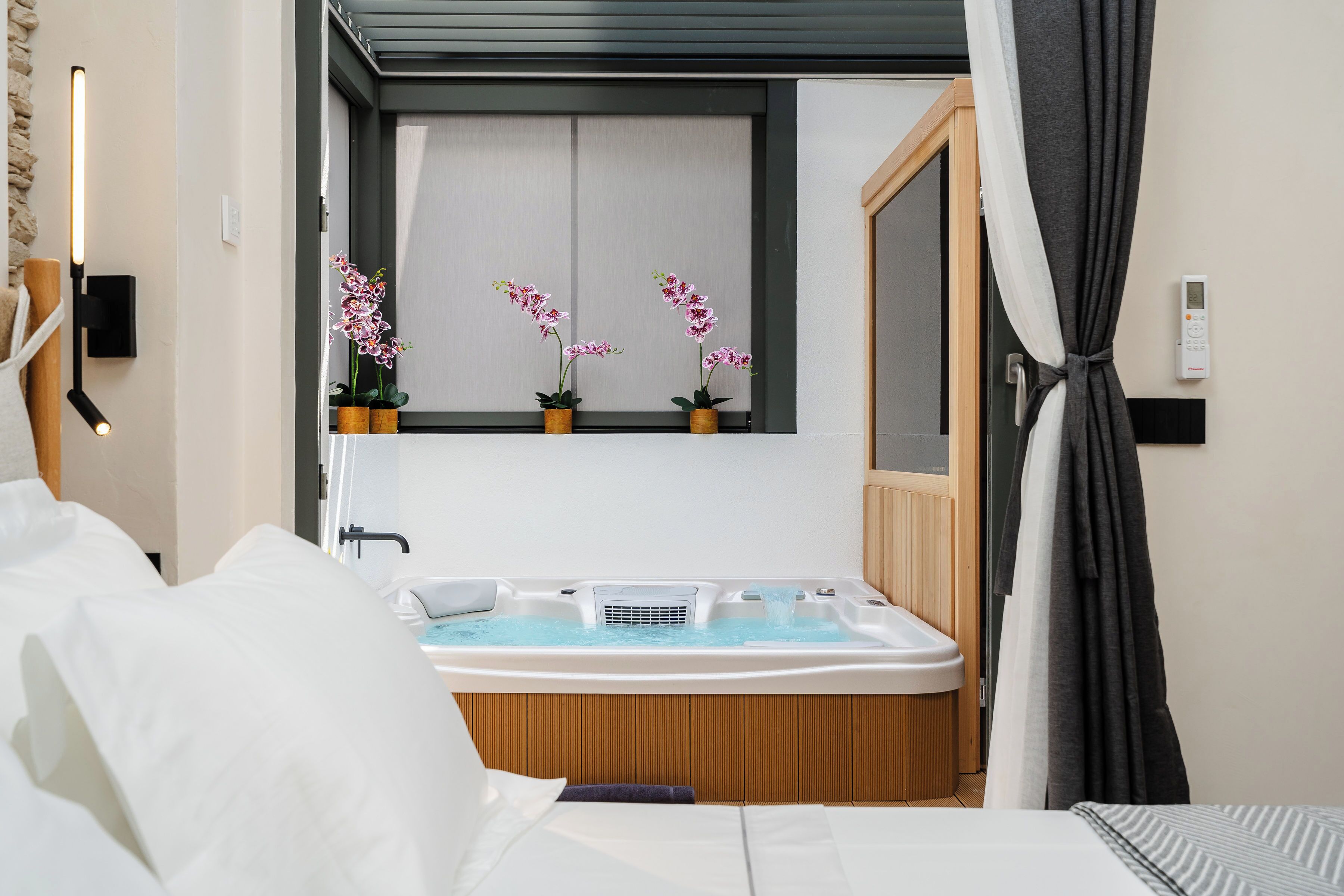 Un baño moderno con bañera, ducha y retrete. Hay orquídeas en macetas en el alféizar de la ventana.