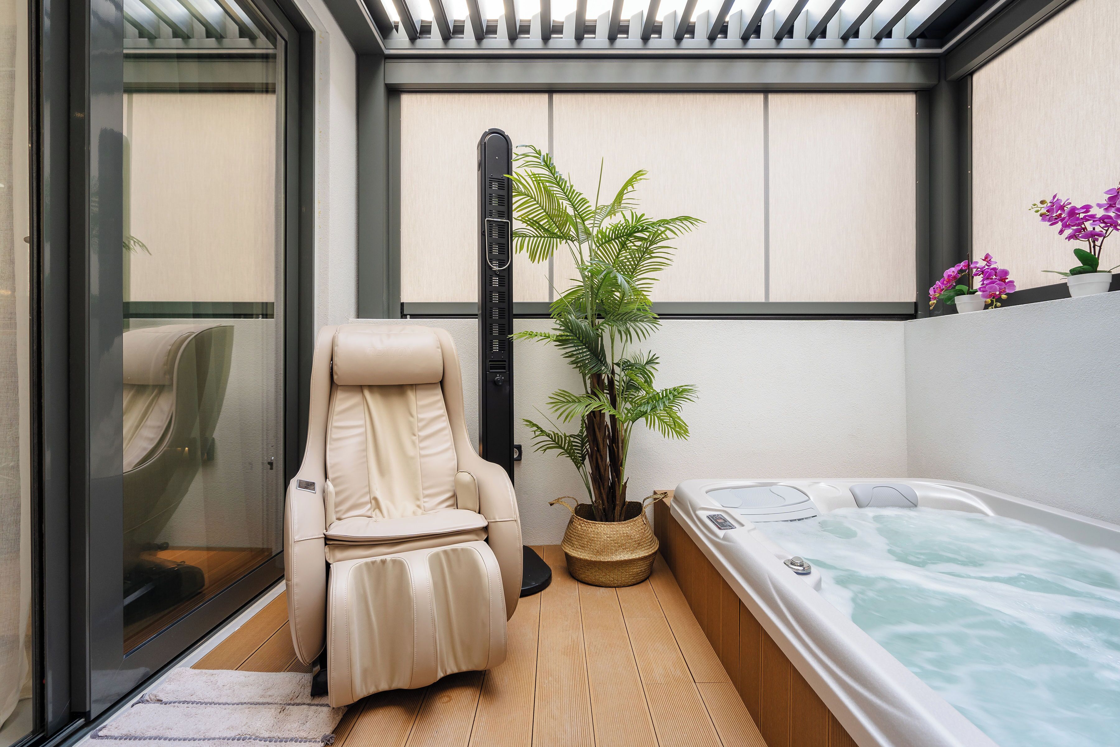 A spa room with a massage chair, a hot tub, and a potted plant.