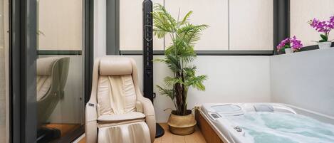 A spa room with a massage chair, a hot tub, and a potted plant.