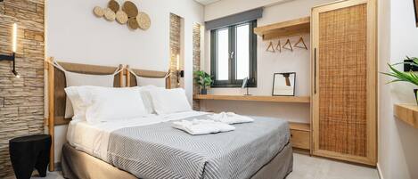 A modern bedroom with a large bed, a stone accent wall, a wooden headboard, and a large window.