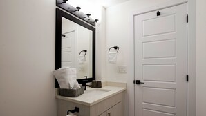 A bathroom with a white sink, a mirror, a towel rack, and a door. - Adorable 1 bedroom suite - 8mins from West Edmonton Mall (Edmonton)