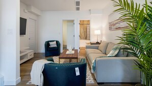 A living room with a sofa, a chair, a coffee table, and a large plant. - Adorable 1 bedroom suite - 8mins from West Edmonton Mall (Edmonton)