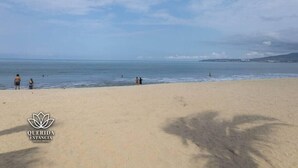Una playa con el logo de 'QUERIDA ESTANCIA' en la esquina inferior izquierda.