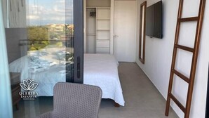 Un dormitorio moderno con cama, sillón, televisor y armario.