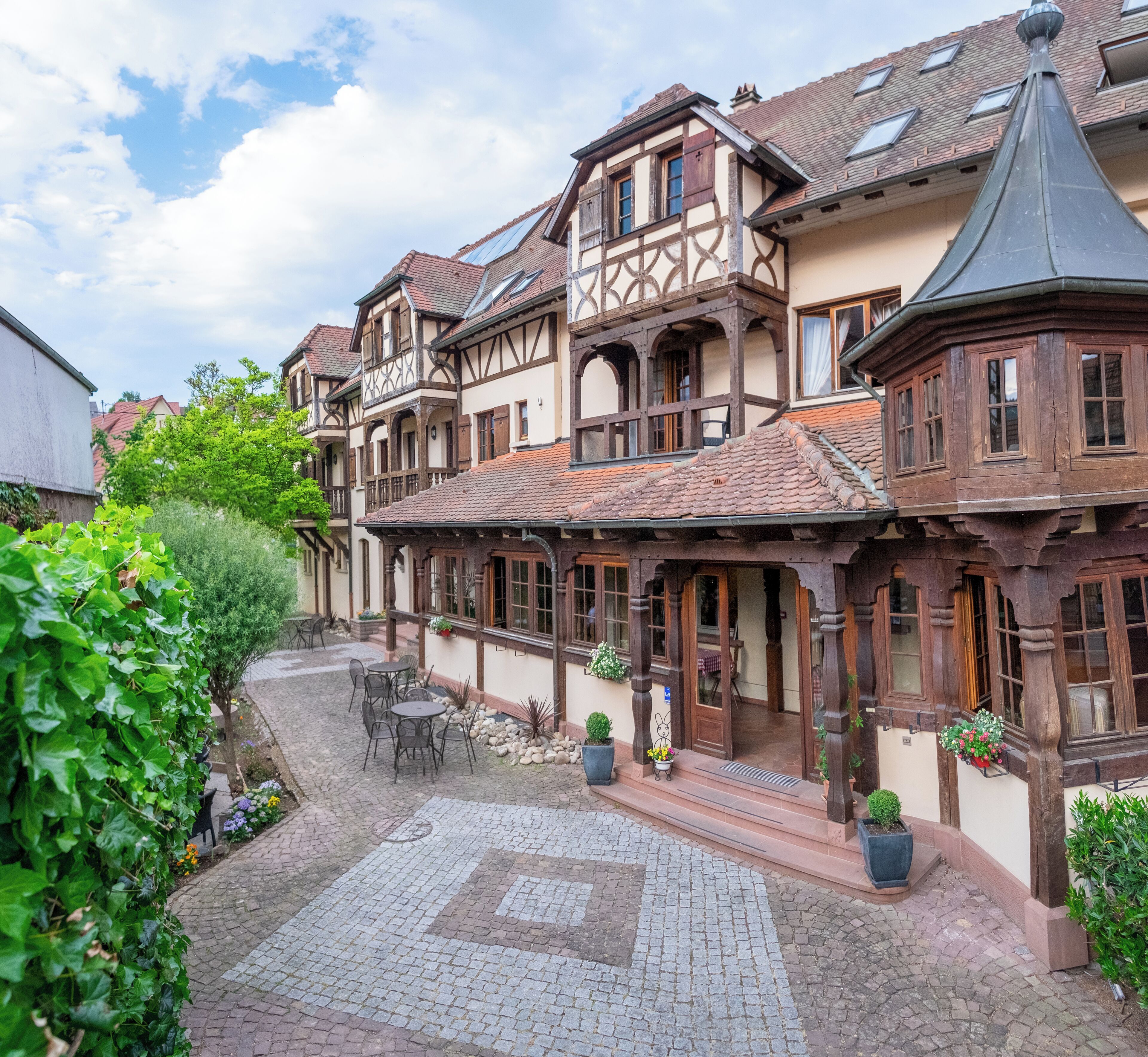 Il s’agit d’un bâtiment européen traditionnel doté d’une cour intérieure, avec une zone pavée de pierres, des espaces de repos en plein air et des plantes en pot.