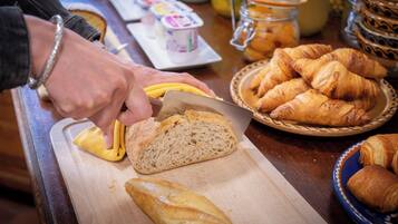 A person slicing a baguette on a wooden cutting board.