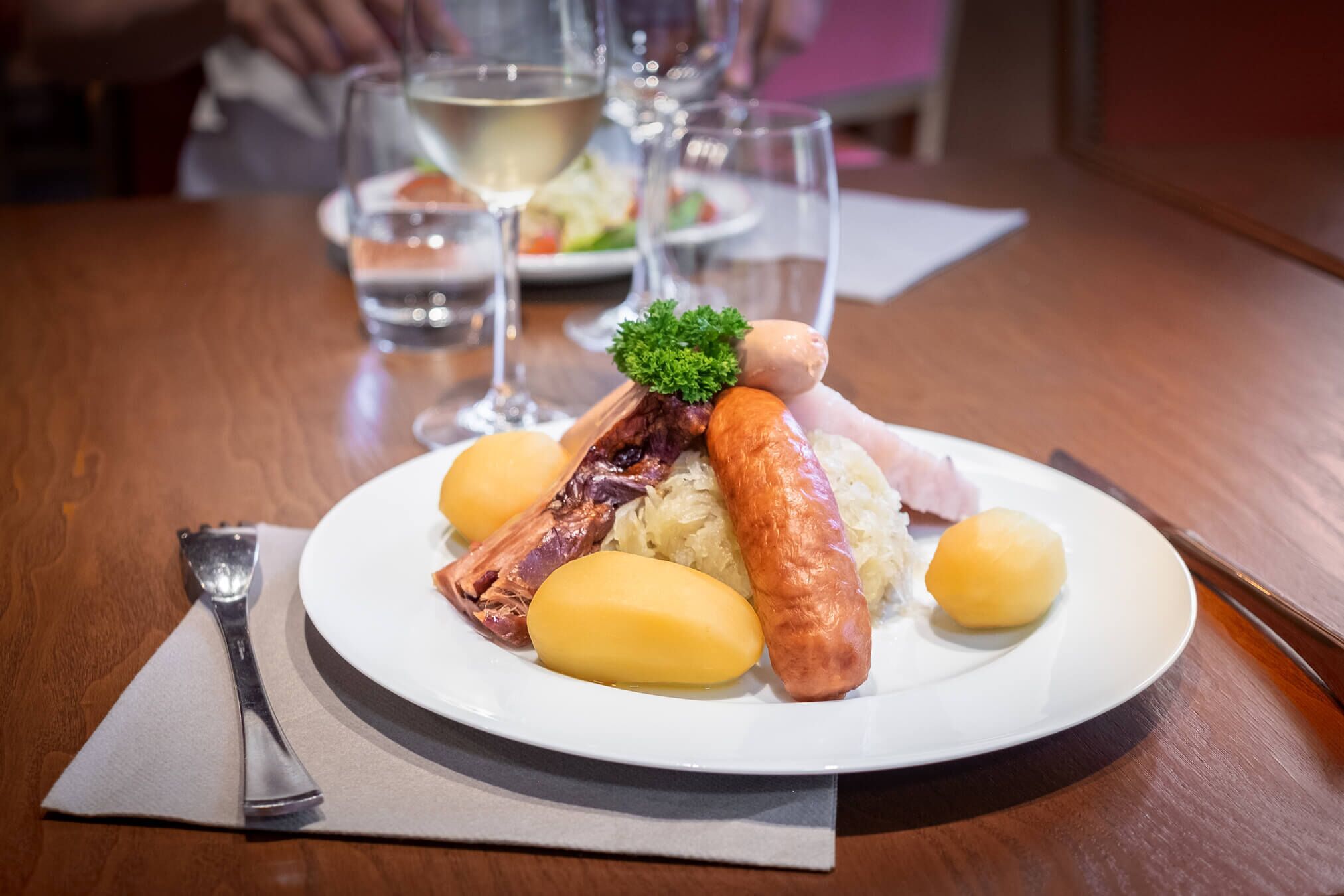 A plate of food with sausages, potatoes, and meat on a wooden table.