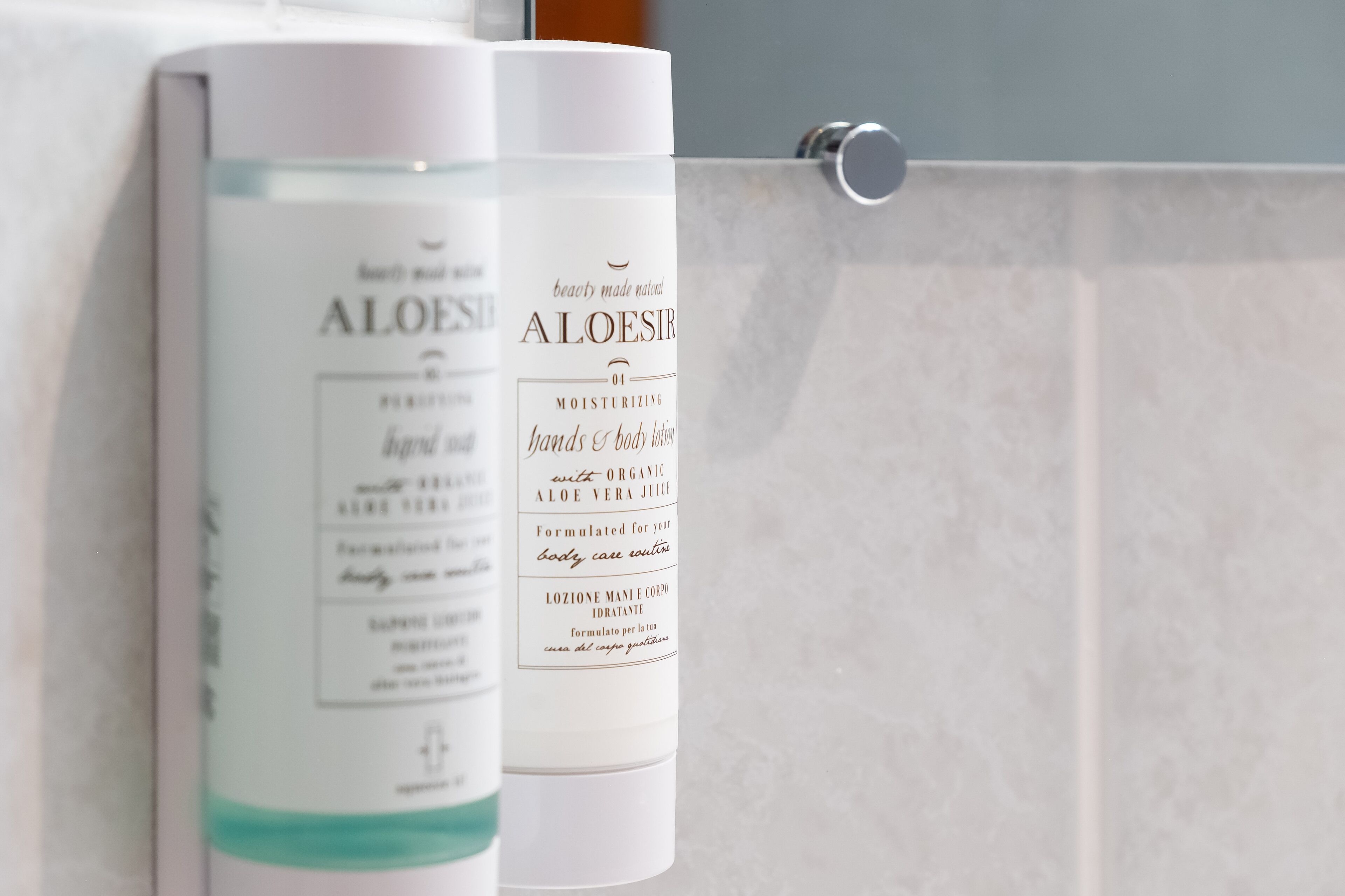 Two bottles of Aloe Vera Moisturizing lotion on a bathroom counter.