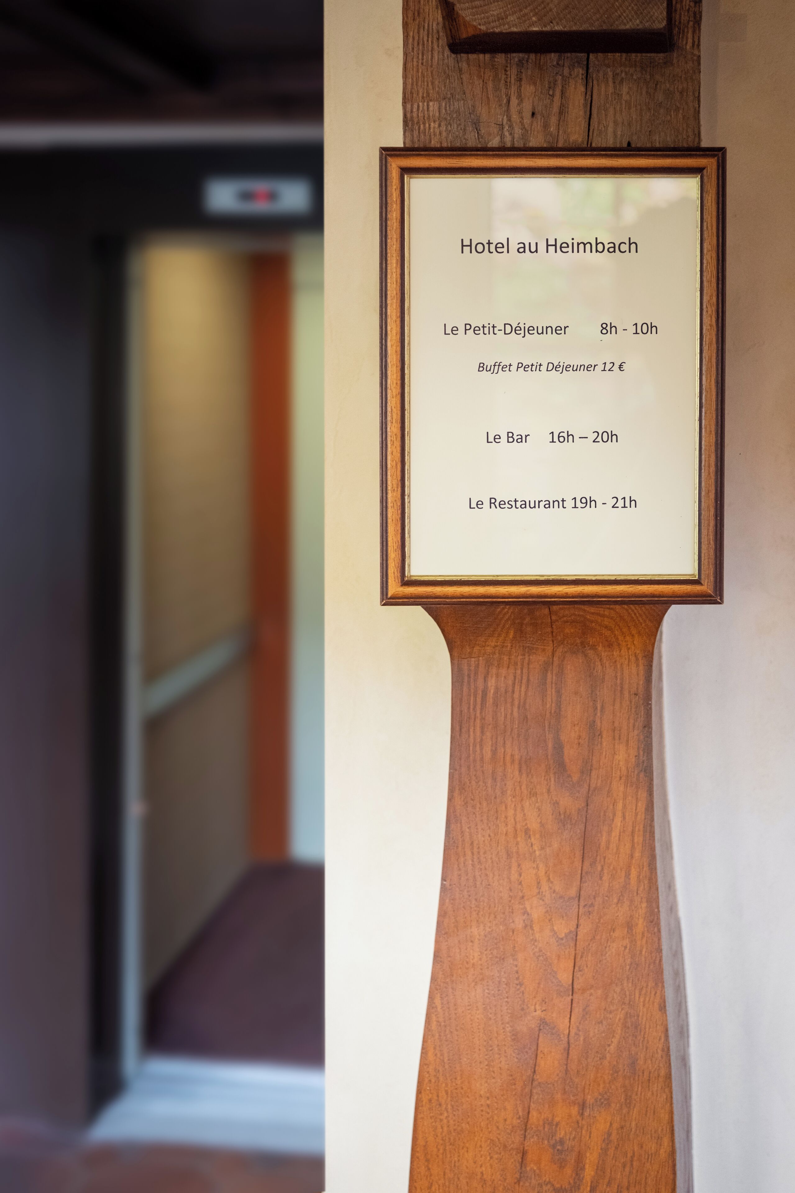 Kehyksiin asetettu kyltti, jossa on Hotel au Heimbachin palveluiden aukioloajat.